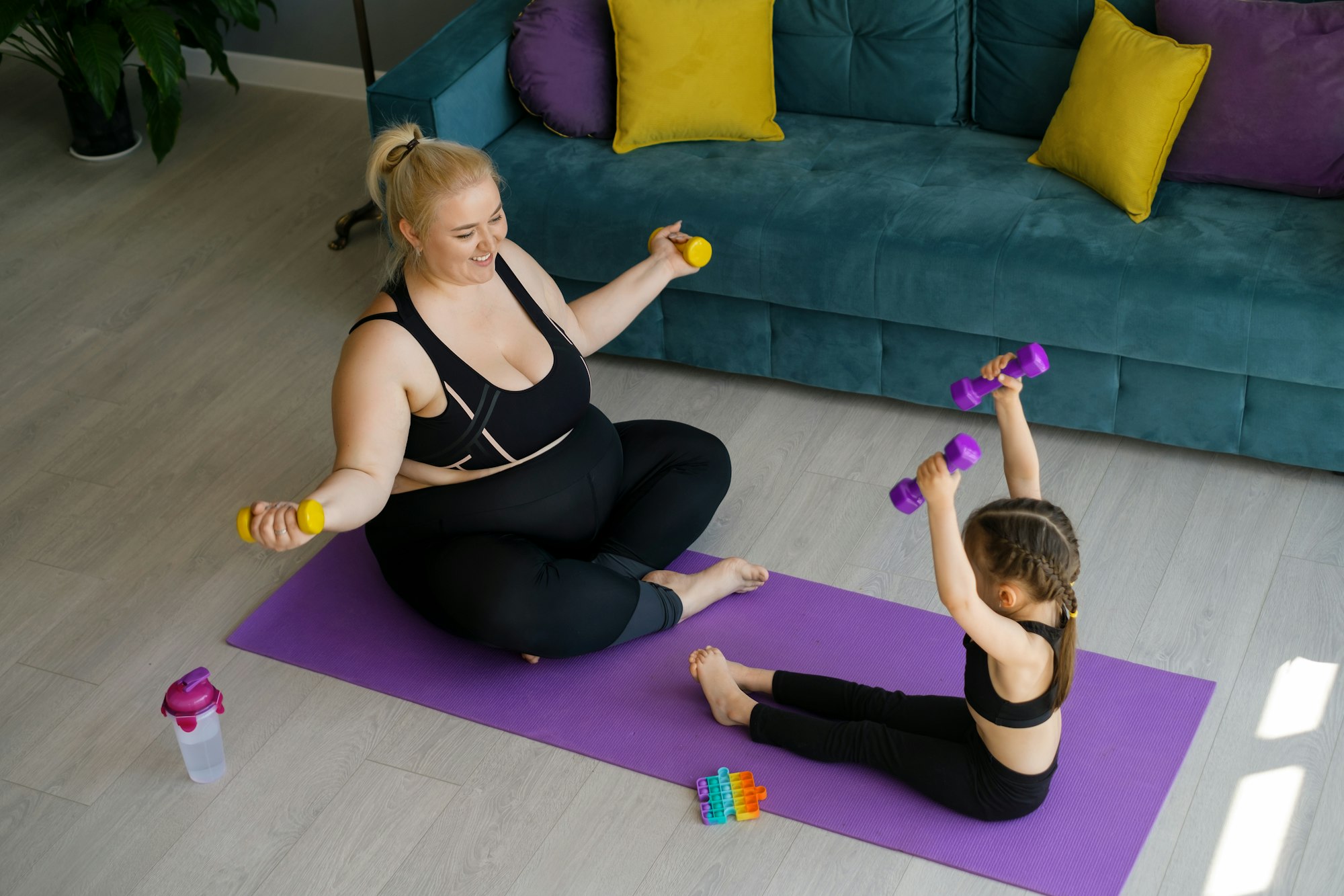 Obese Woman with the daughter Doing sports with dumbbells at home