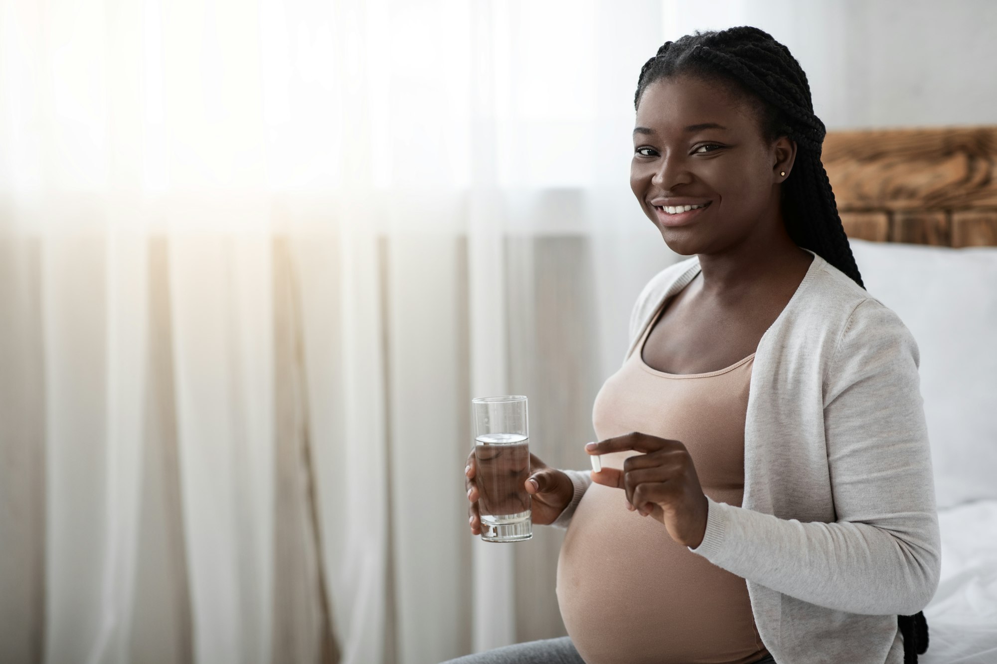 Prenatal Vitamins. Pregnant Black Woman Holding Supplement Pill And Glass Of Water