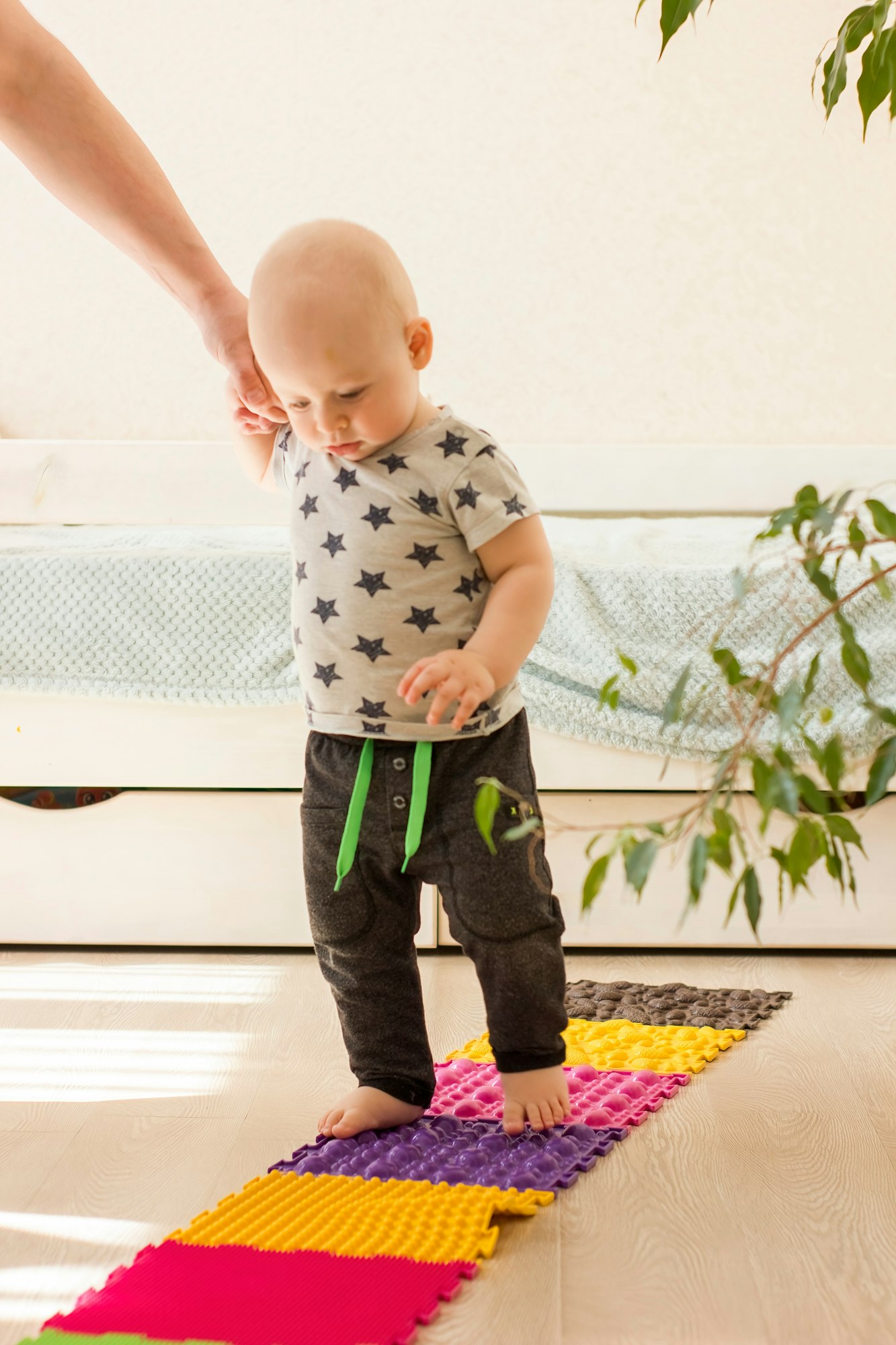 Toddler walks on orthopedic massage mat. Baby foot massage. Exercises for legs on carpet.
